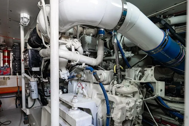 Slide: The Image of Engine room of a 1998 Bertram 60 Convertible yacht, showcasing complex machinery and piping. - 46