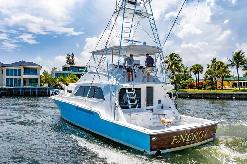 Slide: The Image of 1998 Bertram 60 Convertible yacht cruising near waterfront homes under a sunny sky. - 7