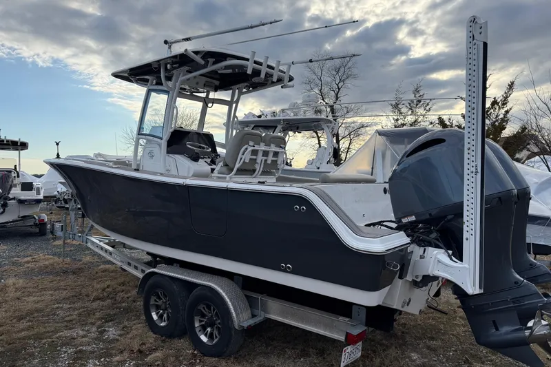 The Image of 2021 Sportsman Heritage 251 Center Console boat on trailer under cloudy sky. - 0