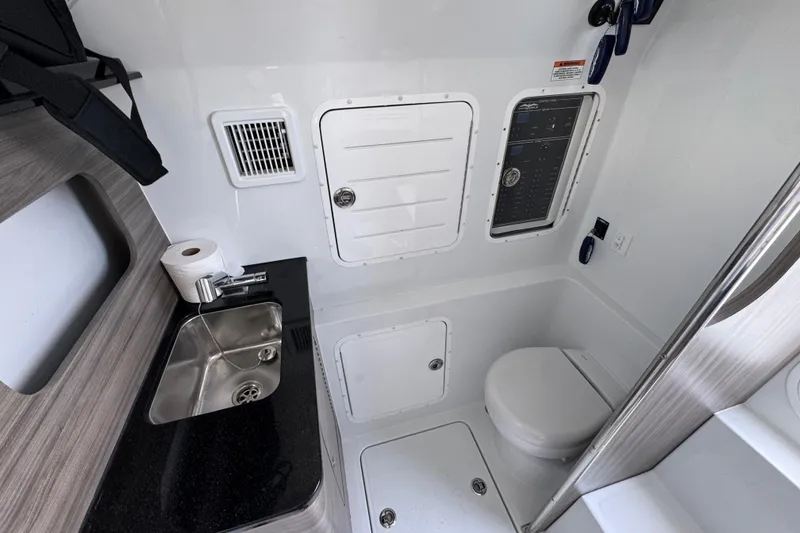 Slide: The Image of 2026 Invincible 43 Open Fisherman boat bathroom with sink, toilet, and storage compartments. - 34
