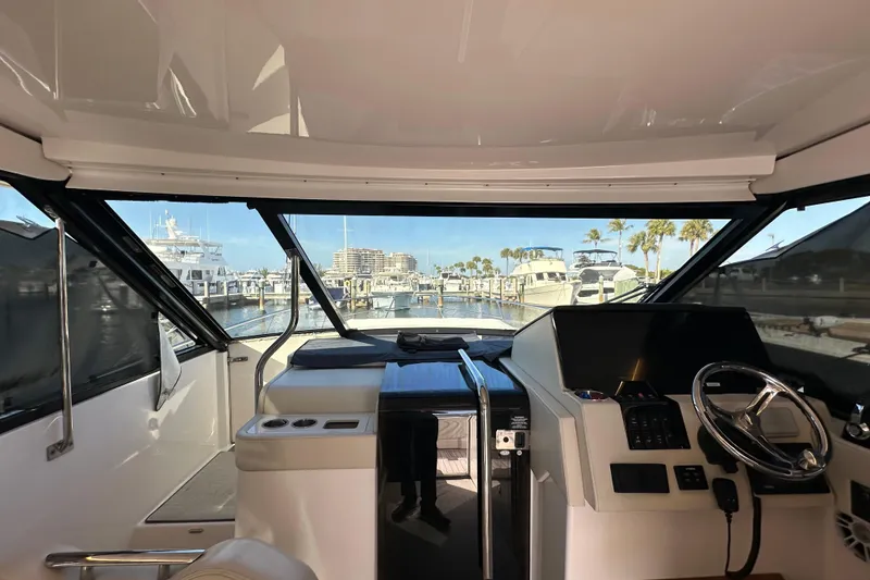 Slide: The Image of 2021 Regal 36 XO yacht interior with helm, marina view, and modern dashboard. - 16