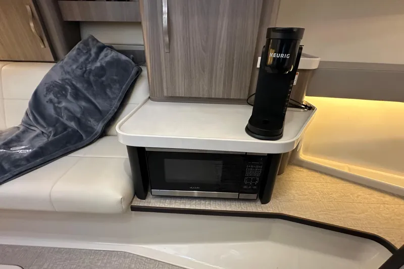 Slide: The Image of 2021 Regal 36 XO yacht interior with microwave, Keurig coffee maker, and cozy seating area. - 25