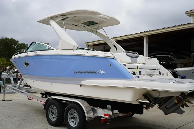 Slide: The Image of 2024 Chaparral 287 SSX boat on trailer, blue and white design, parked outdoors. - 2