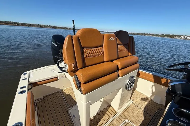 Slide: The Image of 2025 Scout 261 XSS boat interior with tan seating and Mercury engine on a sunny day. - 12