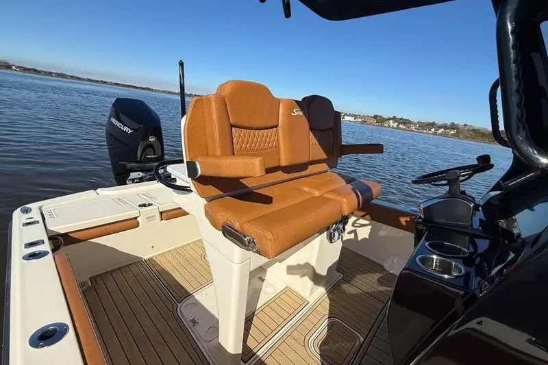 Slide: The Image of 2025 Scout 261 XSS boat interior with tan seats and Mercury engine on a sunny day. - 14