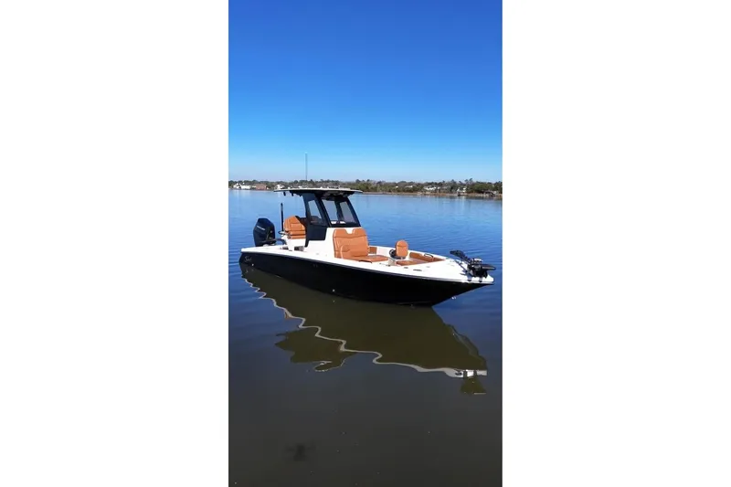Slide: The Image of 2025 Scout 261 XSS boat on calm water under clear blue sky. - 2