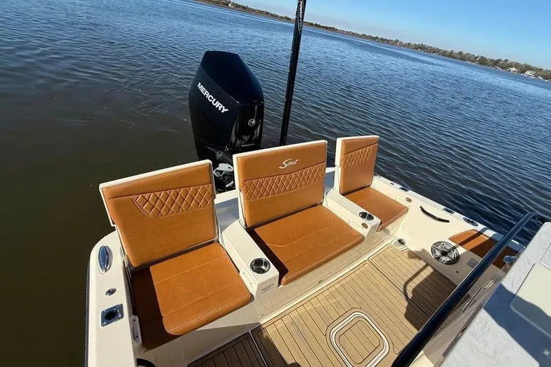 Slide: The Image of 2025 Scout 261 XSS boat with tan seating and Mercury engine on calm water. - 6