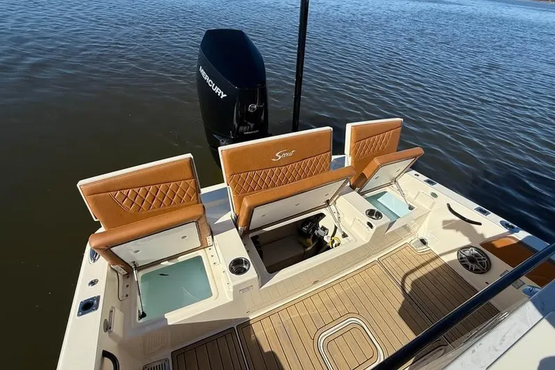 Slide: The Image of 2025 Scout 261 XSS boat with open storage, tan seats, and Mercury engine on water. - 7