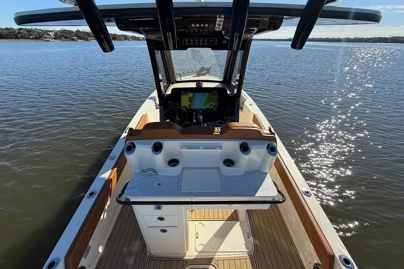 Slide: The Image of 2025 Scout 261 XSS boat interior with console, on calm water, under clear sky. - 8