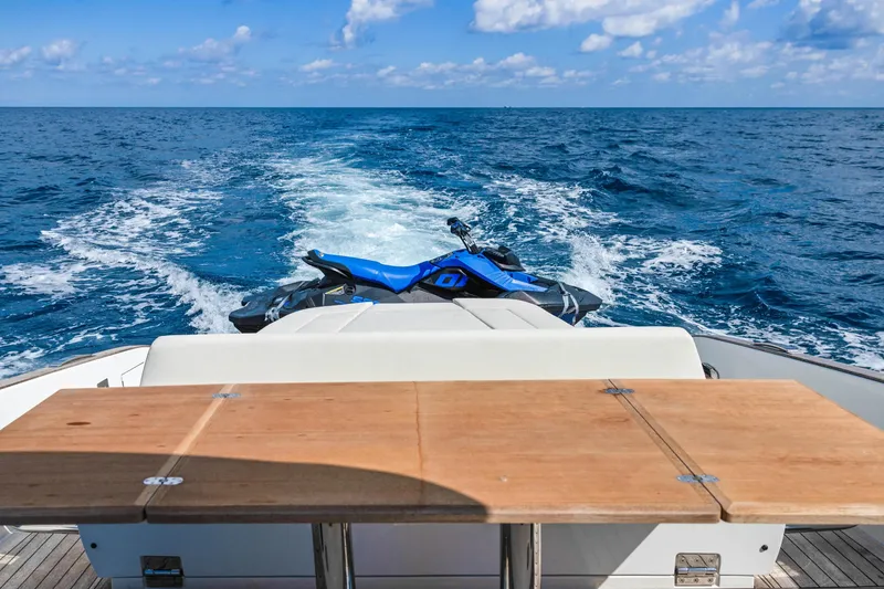 Slide: The Image of 2024 Solaris Power 44 Open yacht with jet ski on ocean, wooden table in foreground. - 7