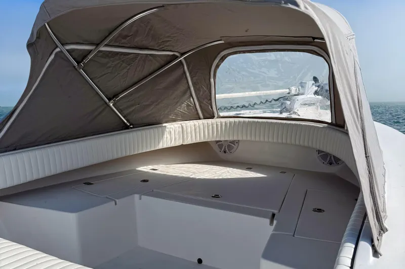 Slide: The Image of 2019 Aquasport 244 Bay boat interior with canopy, featuring cushioned seating and storage compartments. - 13