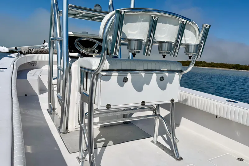 Slide: The Image of 2019 Aquasport 244 Bay boat interior with seating and rod holders on a sunny day. - 26