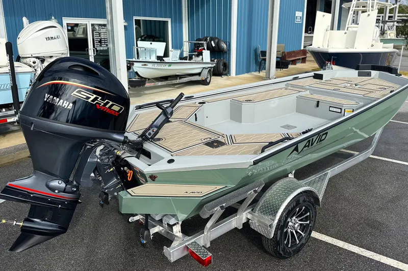 The Image of 2026 Avid 18 Commander boat with Yamaha engine on a trailer, parked outside a marine shop. - 0