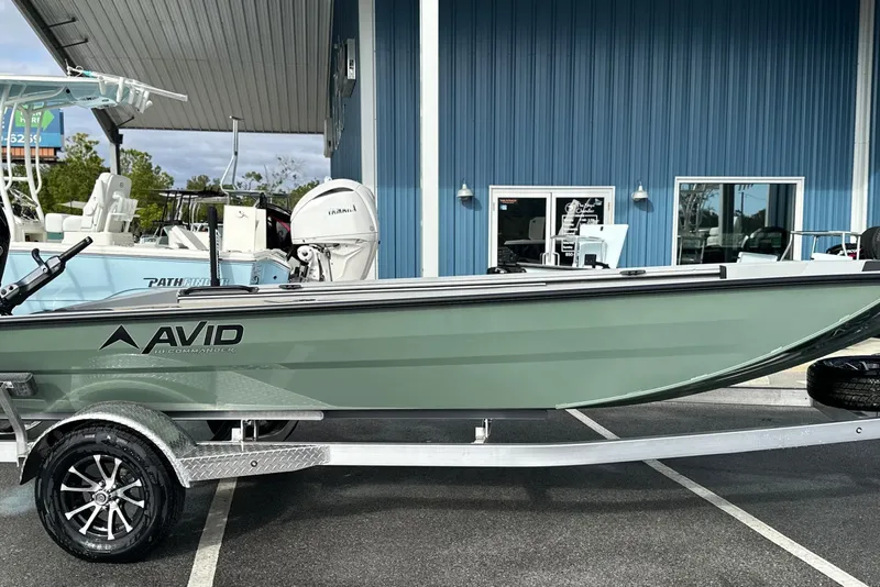 Slide: The Image of Avid 18 Commander 2026 boat on trailer, parked outside a blue building. - 11