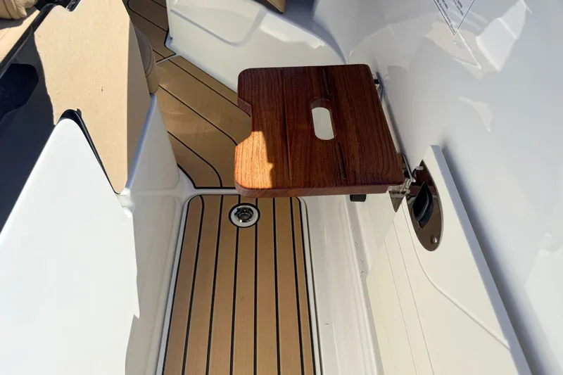 Slide: The Image of 2026 Sea Ray SLX 260 Outboard with wooden foldable table and teak flooring. - 13