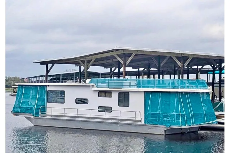 Slide: The Image of 1986 Stardust Cruisers 52 houseboat with blue canopy docked at marina. - 2
