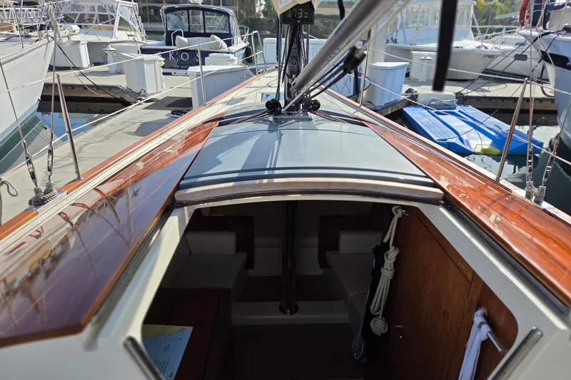 Slide: The Image of 2018 Tofinou 12 sailboat interior view at marina, showcasing sleek wooden deck. - 11
