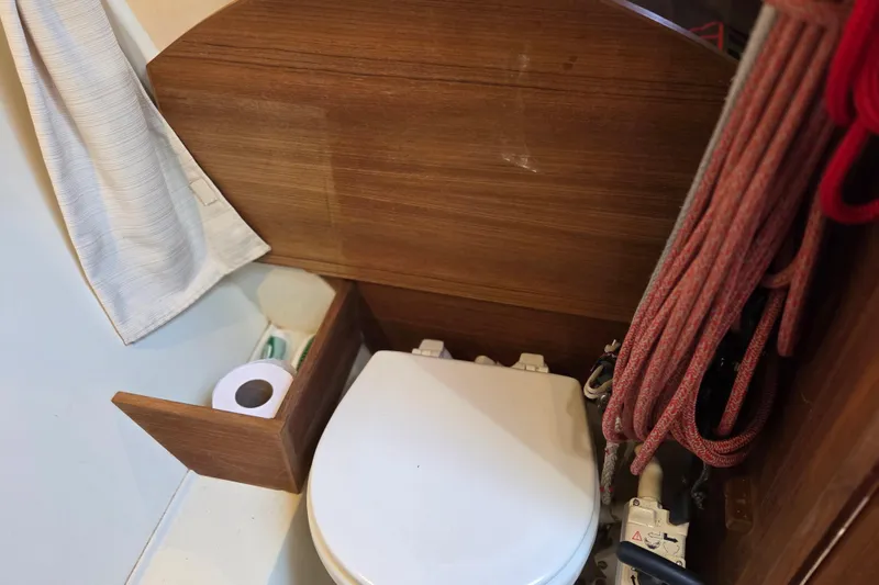Slide: The Image of Compact marine toilet area in 2018 Tofinou 12 sailboat, featuring wooden paneling and nautical ropes. - 17