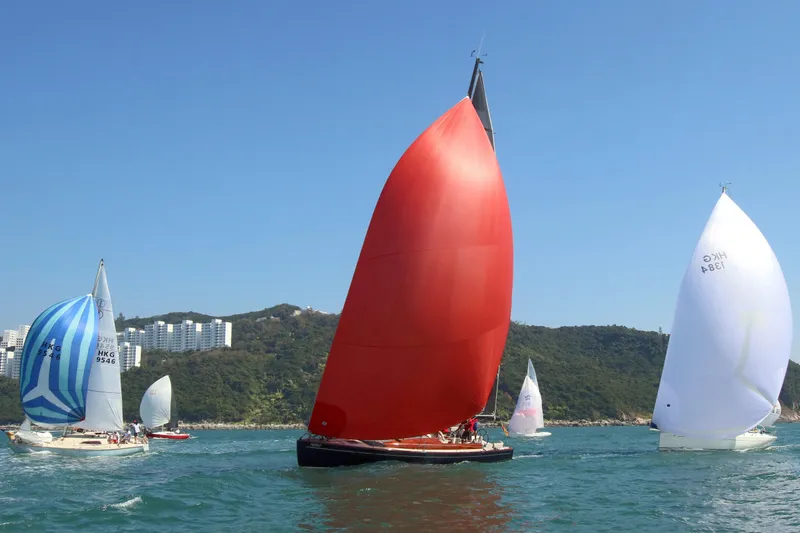 Slide: The Image of Sailboats racing on a sunny day, featuring a 2018 Tofinou 12 with a red sail. - 2