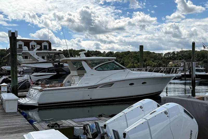 Slide: The Image of 2004 Tiara Yachts 4200 Open docked at a marina under a partly cloudy sky. - 4