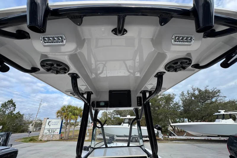 Slide: The Image of 2022 Sea Born LX24 Center Console boat with T-top speakers and lights, parked outdoors. - 33