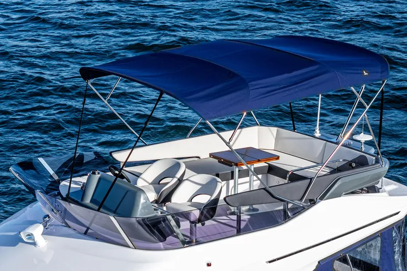 Slide: The Image of 2024 Bavaria R40 boat with canopy, featuring sleek seating and table, on calm blue water. - 22