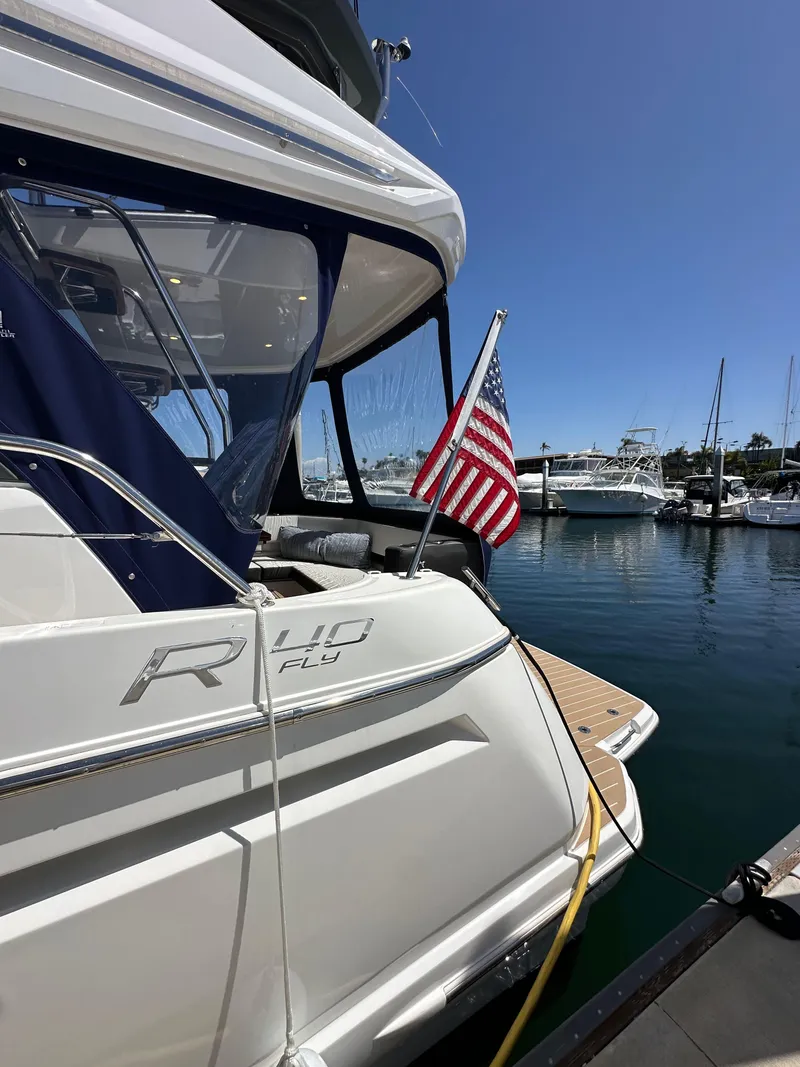 Slide: The Image of 2024 Bavaria R40 yacht docked with American flag, sunny marina background. - 36