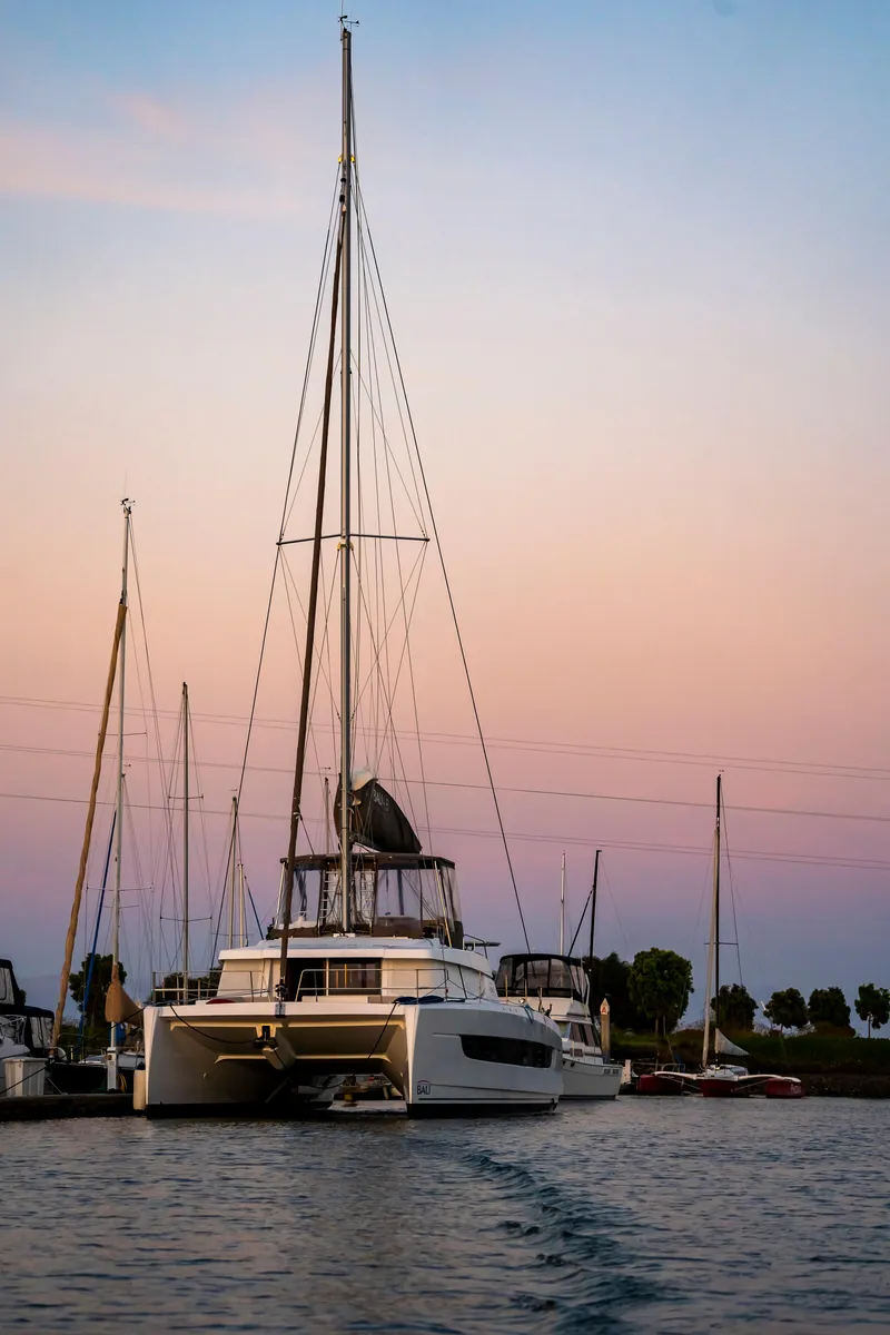 Slide: The Image of 2021 Bali 4.8 catamaran at sunset in a serene marina setting. - 4