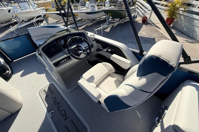 Slide: The Image of 2026 Avalon 2385 LSZ Quad Lounger boat interior with steering console and plush seating. - 24