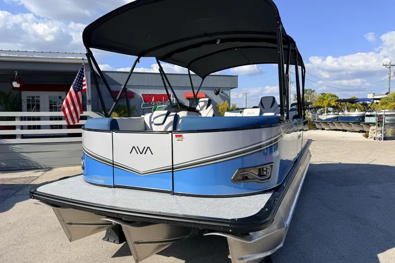 Slide: The Image of 2026 Avalon 2385 LSZ Quad Lounger Tri Toon boat, blue and white, parked outdoors. - 3