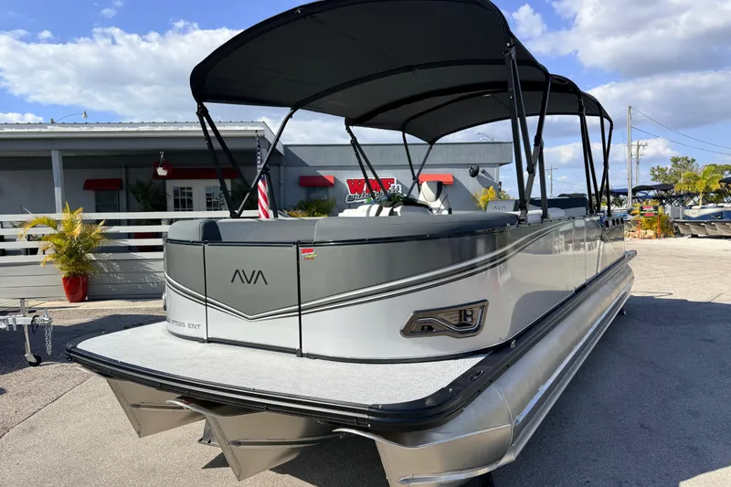Slide: The Image of 2026 Avalon 2585 LSZ Entertainer Tri Toon boat with canopy, parked outdoors. - 2