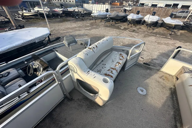 Slide: The Image of 2006 Sun Tracker Party Barge 21 Signature Series with worn seating, docked among covered boats. - 14