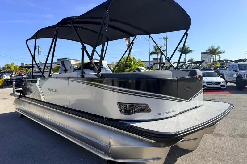 Slide: The Image of 2026 Avalon 2385 LSZ Quad Lounger Tri Toon boat with canopy, parked outdoors. - 5