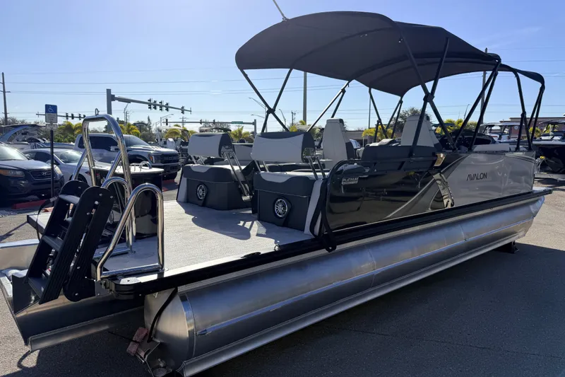 Slide: The Image of 2026 Avalon 2385 LSZ Quad Lounger Tri Toon boat with canopy, parked outdoors. - 6