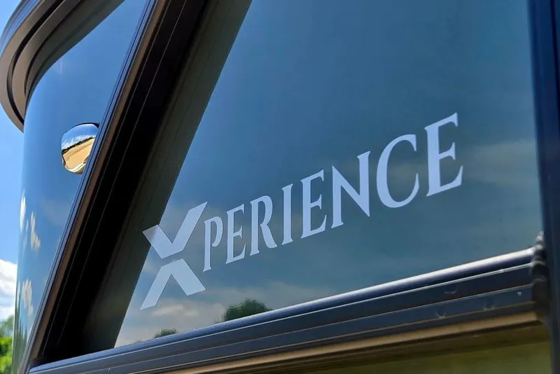 Slide: The Image of 2025 Godfrey Xperience 2086 SFLX boat, close-up of logo on sleek exterior. - 8