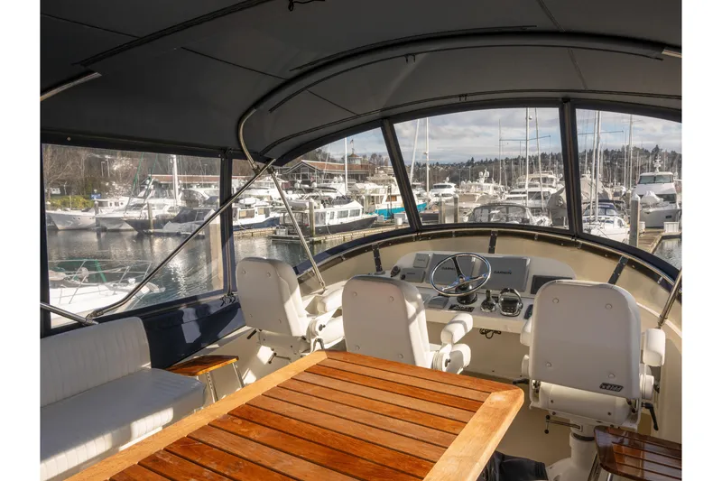 Slide: The Image of Interior view of 2013 Coastal Craft 45 yacht helm, featuring luxurious seating and marina backdrop. - 14