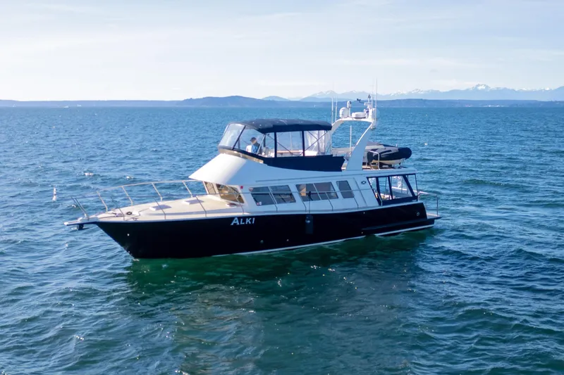 Slide: The Image of 2013 Coastal Craft 45 yacht cruising on open water with scenic mountain backdrop. - 2