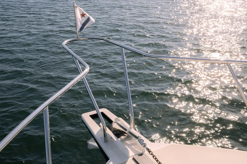 Slide: The Image of Bow of 2013 Coastal Craft 45 yacht with flag, reflecting sunlight on water. - 8