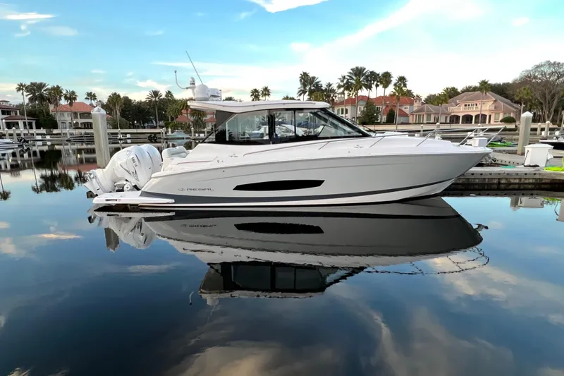 The Image of 2021 Regal 36 XO boat docked in a serene marina, reflecting on calm water. - 0