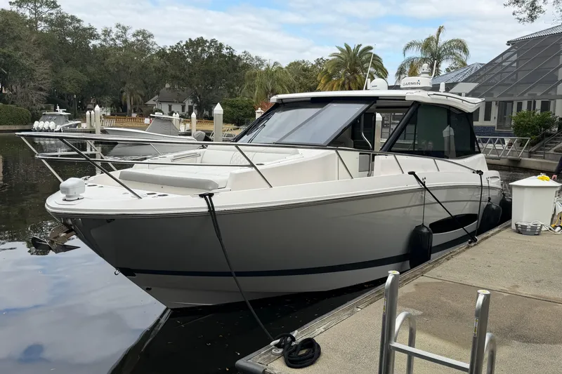 Slide: The Image of 2021 Regal 36 XO boat docked by a scenic waterfront with trees and buildings. - 1