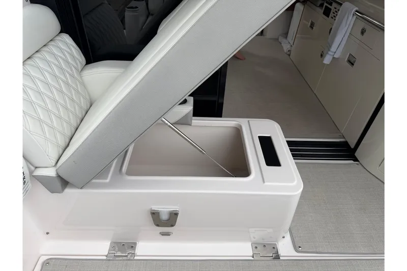 Slide: The Image of 2021 Regal 36 XO boat interior with open storage compartment under cushioned seat. - 11
