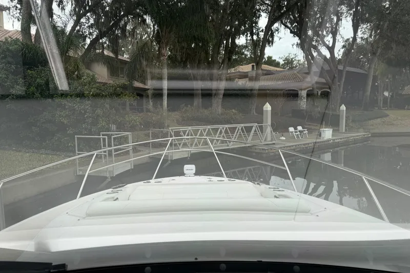 Slide: The Image of 2021 Regal 36 XO yacht docked near a residential area with lush trees. - 37