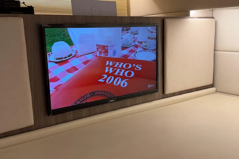 Slide: The Image of TV screen displaying "Who's Who 2006" inside a 2021 Regal 36 XO boat cabin. - 54