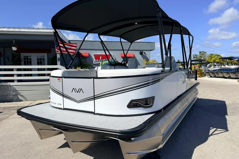 Slide: The Image of 2026 Avalon 2385 LSZ Versatile Rear Bench Tri Toon boat, parked outdoors under blue sky. - 2