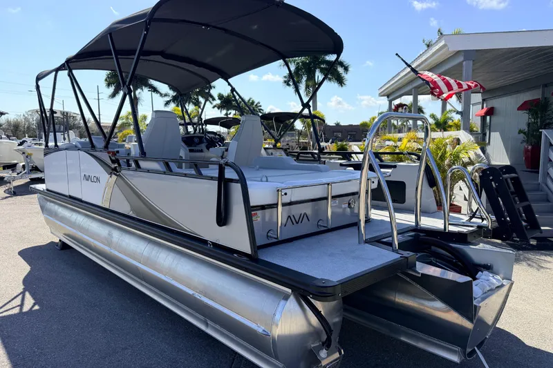 Slide: The Image of 2026 Avalon 2385 LSZ Versatile Rear Bench Tri Toon boat with canopy, parked outdoors. - 9