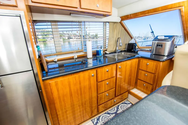 Slide: The Image of Luxurious 2005 Navigator 4400 Pilothouse yacht kitchen with wood cabinetry and waterfront view. - 17