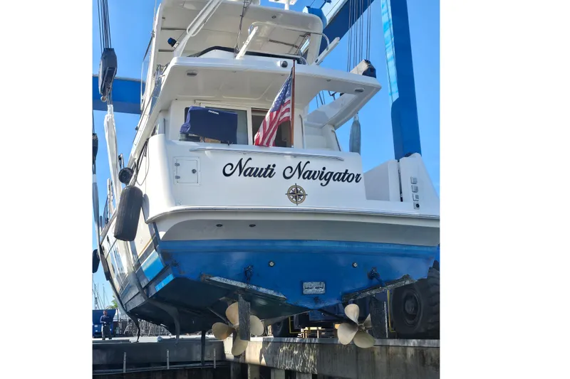 Slide: The Image of 2005 Navigator 4400 Pilothouse boat named "Nauti Navigator" in dry dock with American flag. - 25