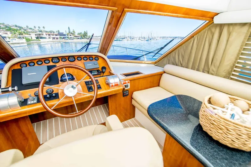 Slide: The Image of 2005 Navigator 4400 Pilothouse interior with wooden helm, plush seating, and scenic marina view. - 9