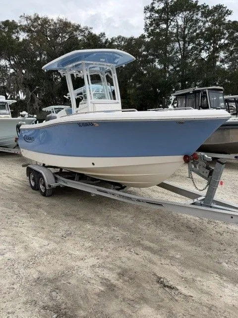 The Image of 2022 Robalo R230 Center Console on trailer, blue and white design. - 1