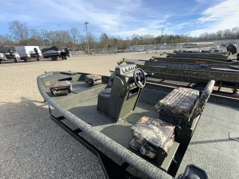 Slide: The Image of War Eagle 961BH CC 2026 boat on gravel lot, featuring camouflage seats. - 4